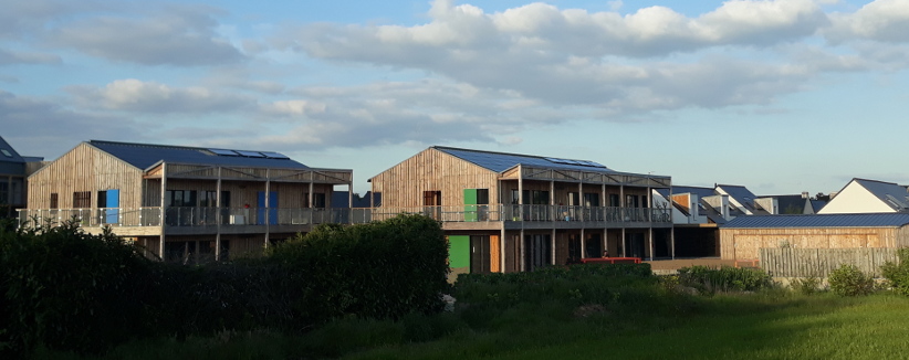 Habitat participatif, Guérande (département 44) : bâtiment bois, large baies vitrées donnant sur des coursives, volets bleus et verts