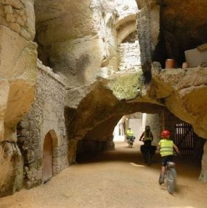 Voie cyclable dans une ancienne rue taillée dans la roche. Le vélo participe du tourisme écologique