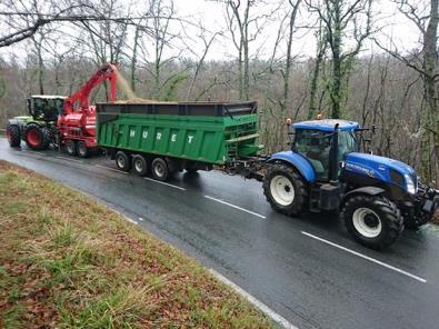 Un tracteur avec remorque et un tracteur avec broyeur : ce dernier évacue du broyat de bois dans la remorque