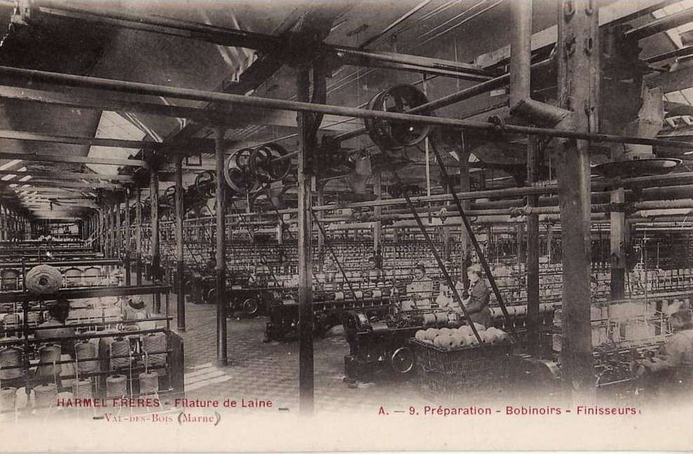 La filière laine au XIXe siècle : carte postale en noir et blanc de la filature Harmel Frère, énorme hangar, machines anciennes à perte de vue, courroies, femmes et bobines de laine au premier plan